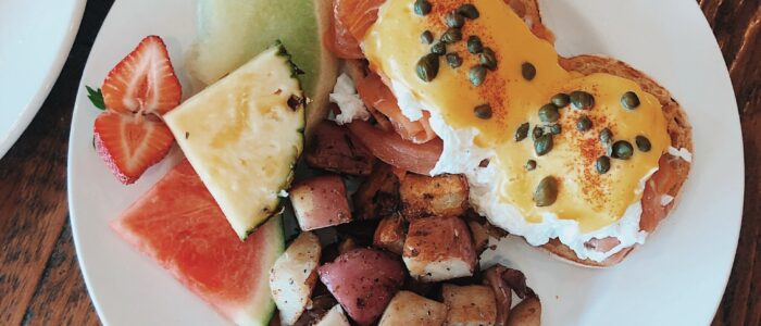 Eggs Benedict with home fries Eggs Benedict with hollandaise, home fries and fresh fruit at Crepes on Cole