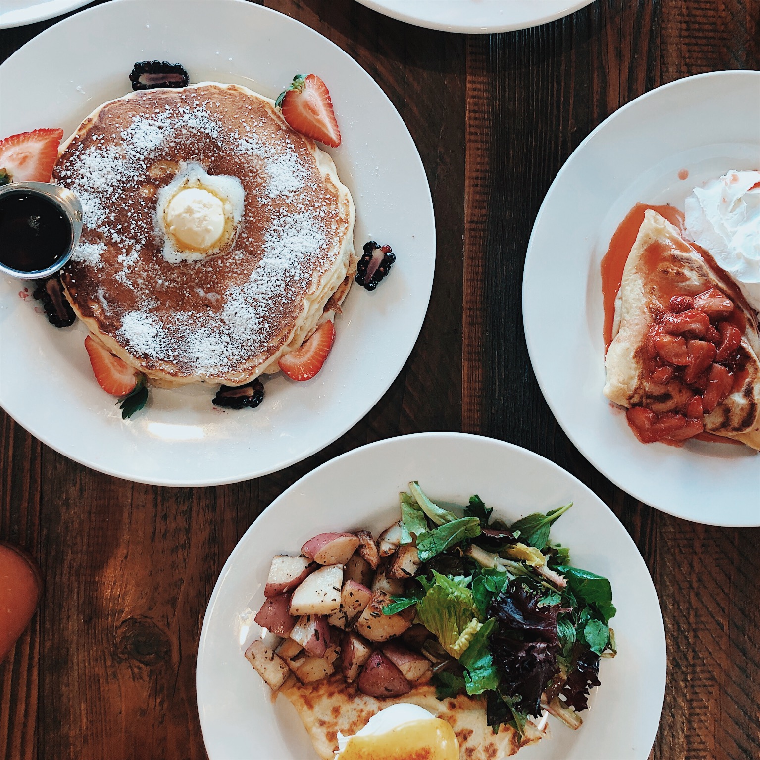 Homemade pancakes with powdered sugar and fresh strawberries beside a strawberry crepe at Crepes on Cole in San Francisco