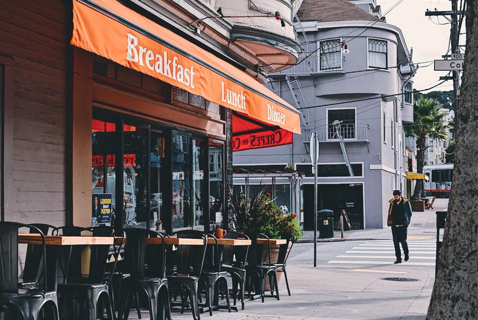 Crepes on Cole storefront at Cole and Carl Streets with its orange awning and sidewalk seating